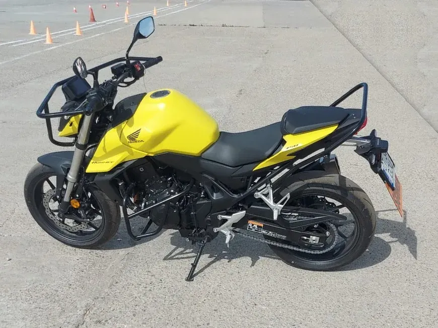 Honda Hornet galbenă pe poligonul de examen, cu jaloanele în fundal