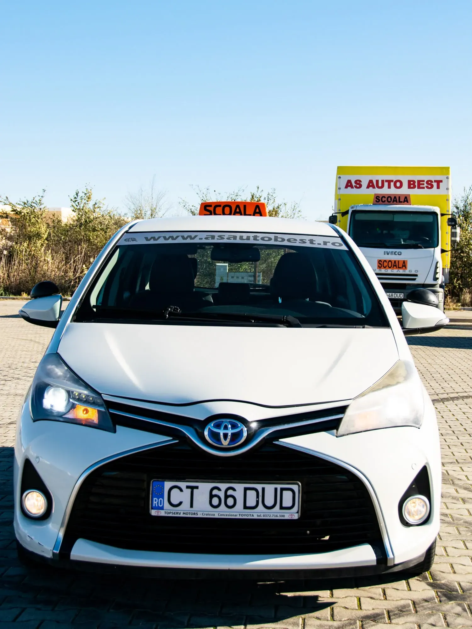 Toyota Yaris de școală văzută din față, cu camionul AS Auto Best în spate